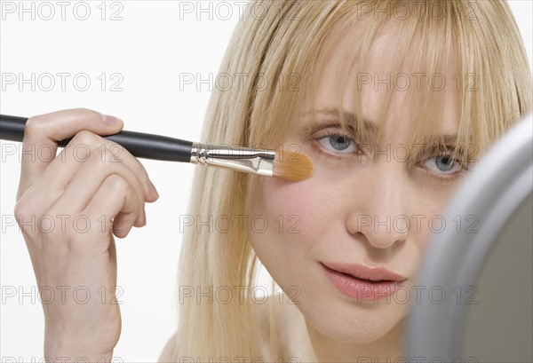 Woman with cosmetic brush and mirror.