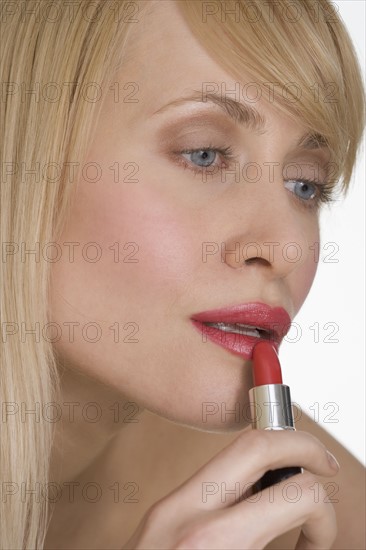 Woman applying red lipstick.