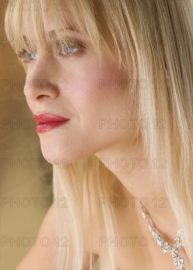 Profile of blond woman wearing necklace.