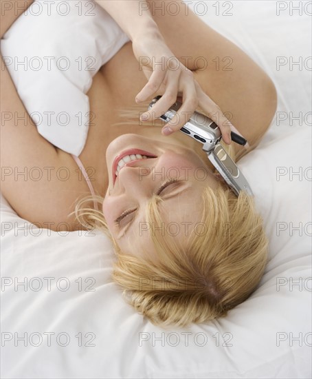 Woman talking on cellphone lying down.