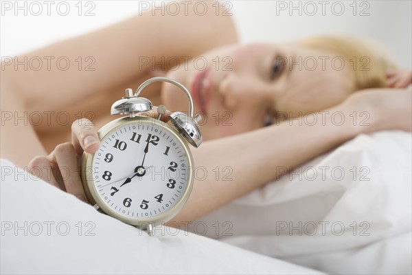 Woman holding alarm clock.