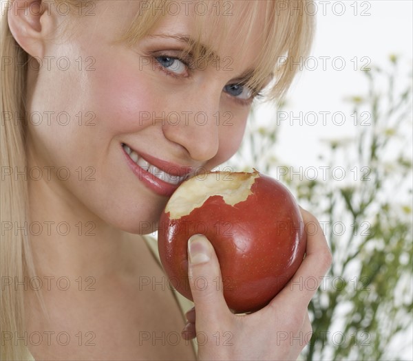 Smiling woman eating apple.