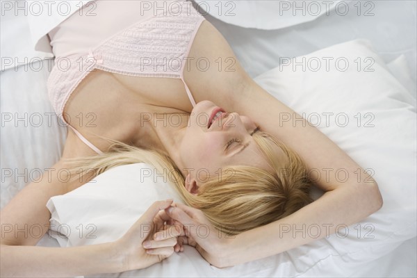 Smiling woman stretching in bed.