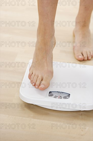 Feet stepping onto bathroom scale.