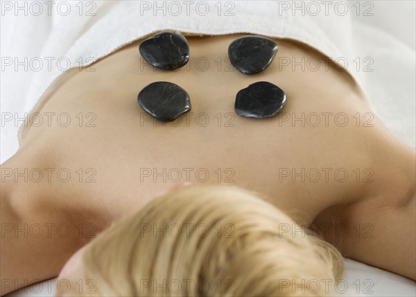 Woman face down with stones on back.