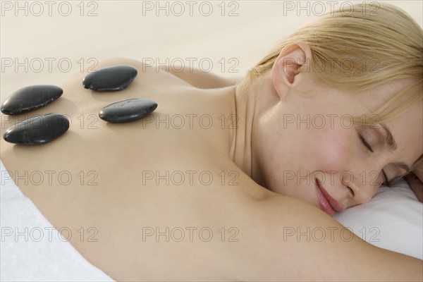 Prone woman with stones on back.