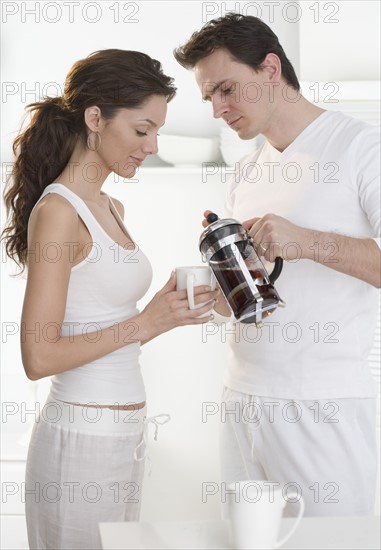 Couple pouring coffee from french press.