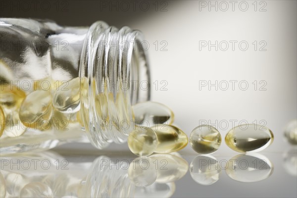 Gelcaps spilling out of glass bottle.