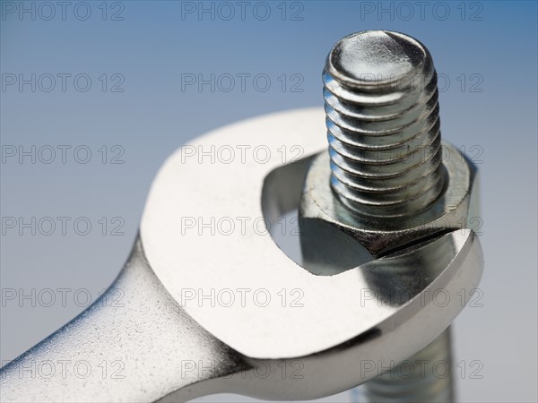 Wrench turning nut on bolt.