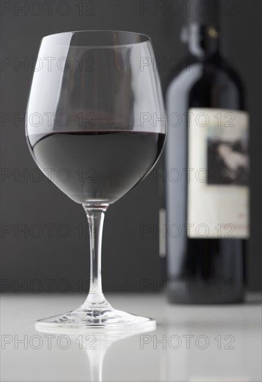 Glass of red wine with bottle.