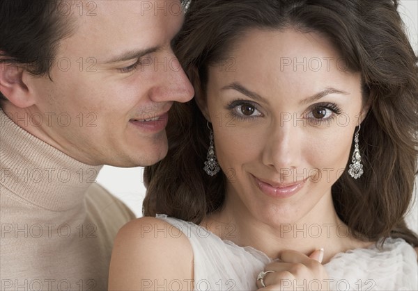 Man whispering in woman's ear.