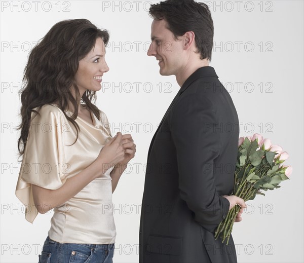 Man hiding bouquet from woman.