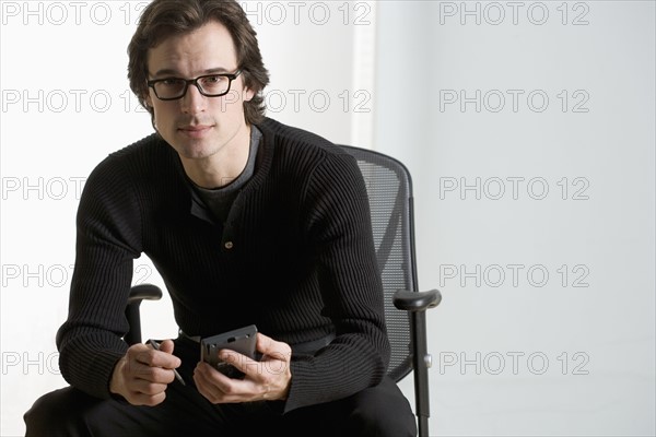 Professional man seated with PDA.