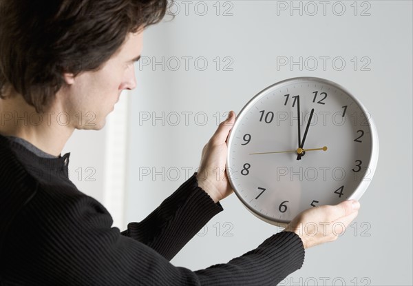 Man holding clock with arms outstretched.