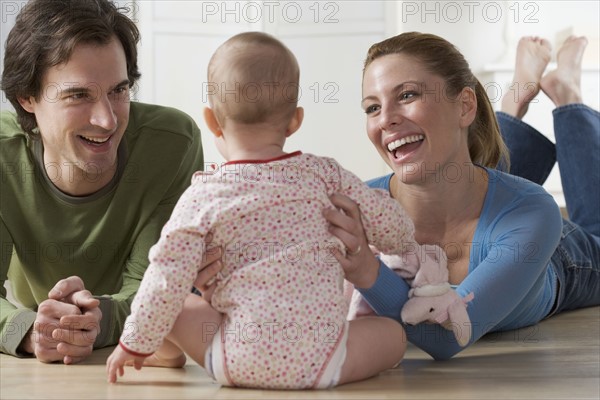 Couple playing with baby on floor.