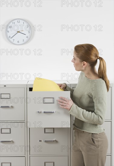 Woman with files looking at clock.