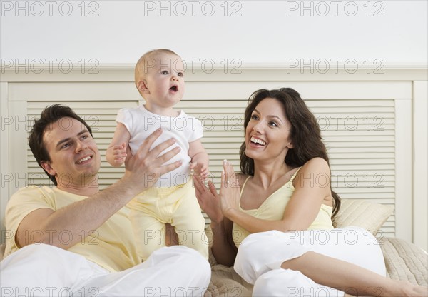 Proud couple lying down with infant.