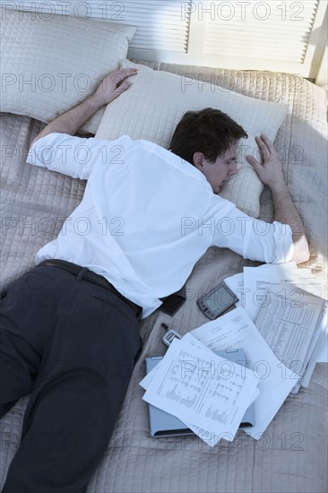 Overworked businessman sleeping with paperwork.