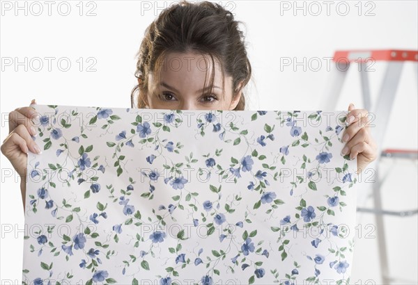 Woman hiding behind piece of wallpaper.