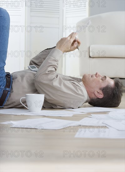 Man writing while lying on floor.