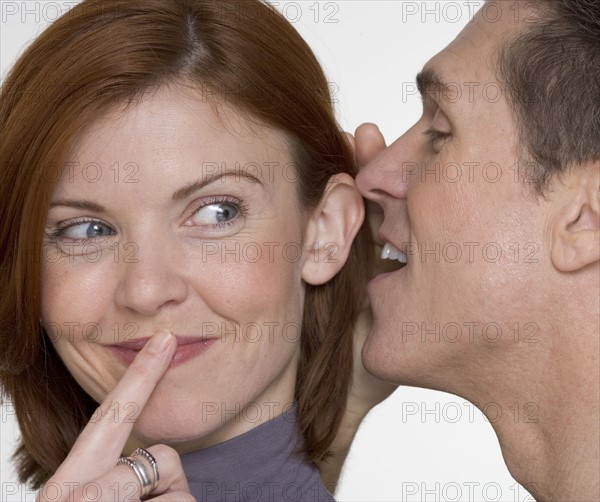 Man whispering secret in woman's ear.