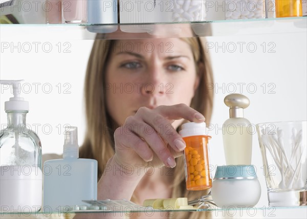 Woman removing medicine from cabinet.