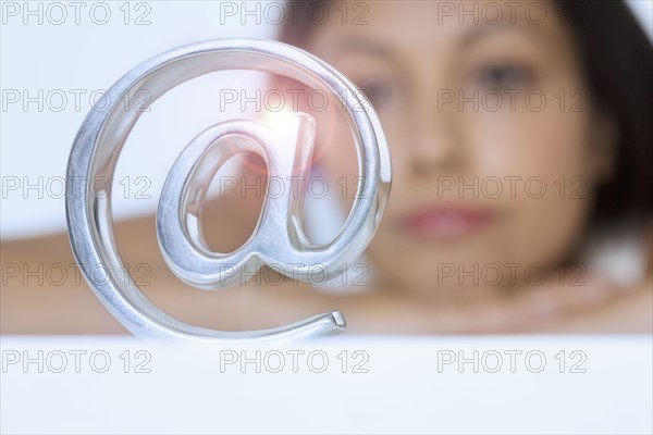 Woman looking at metal @ symbol.