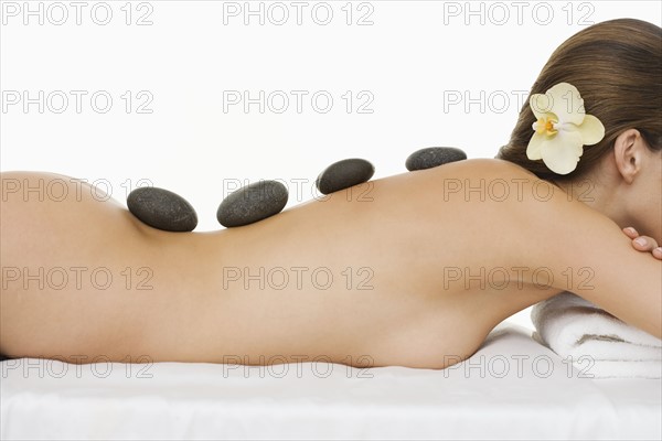 Nude female and warm rock body therapy.