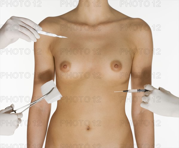 Nude female torso with medical instruments.