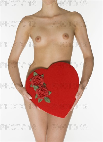 Nude female holding heart shaped box.