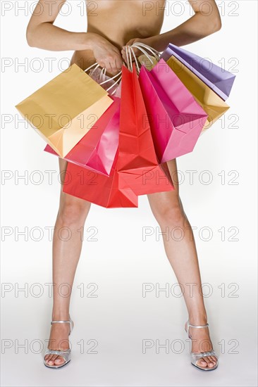 Nude female holding shopping bags.