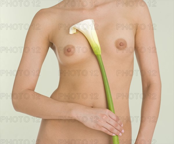 Nude female holding calla lily.