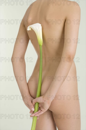 Nude female holding calla lily.