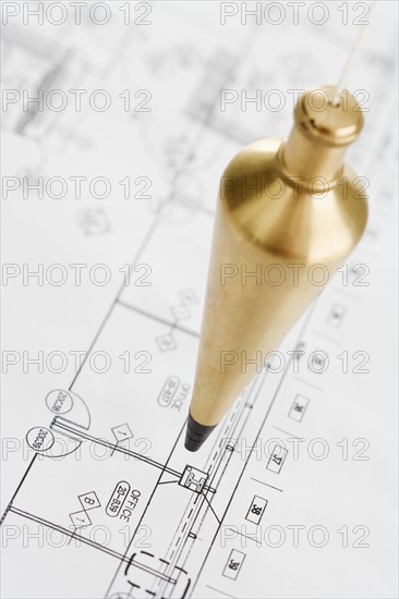 Plumb bob above blueprints.