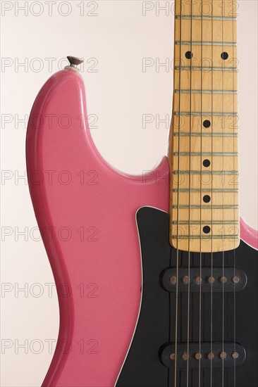 Closeup of pink electric guitar.