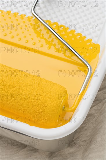Still life of paint roller with yellow paint.