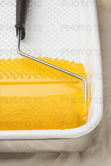 Still life of paint roller with yellow paint.