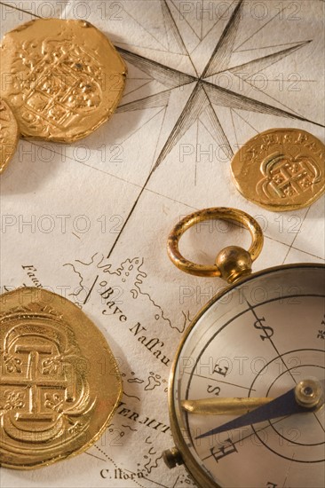 Still life of pieces of gold map and compass.