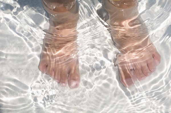 Child's feet standing in water.