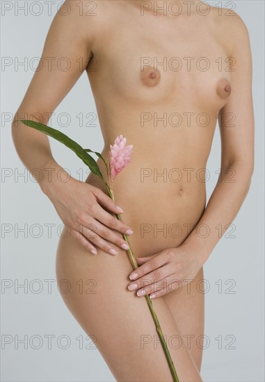 Nude female holding flower.