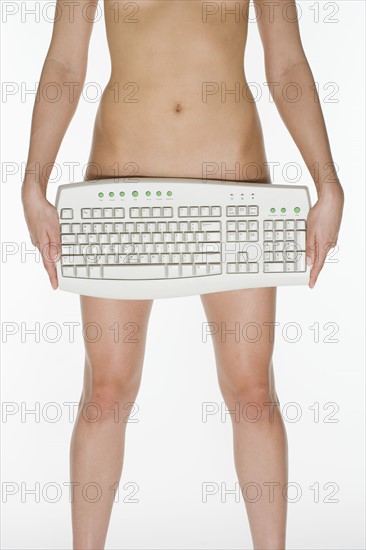 Nude female holding computer keyboard.