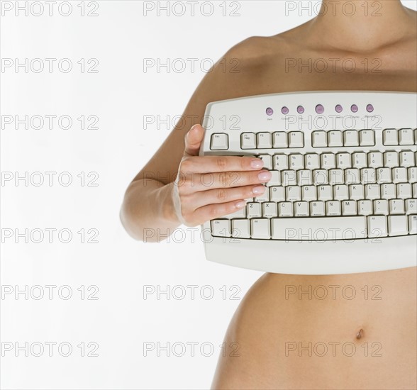 Nude female holding computer keyboard.