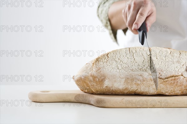 Hand cutting loaf of bread.