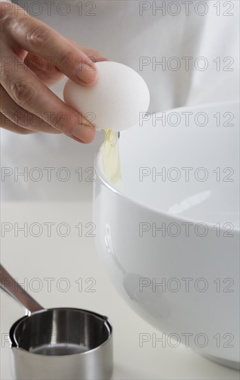 Hand cracking egg into bowl.