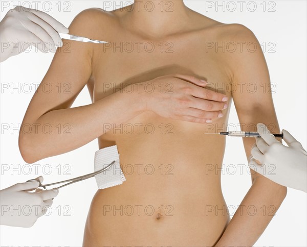 Nude female torso with medical instruments.