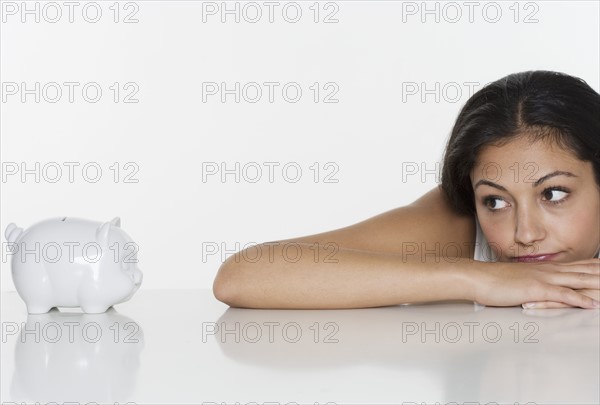 Discouraged woman looking at piggy bank.