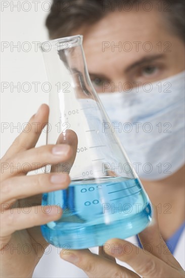 Closeup of scientist examining blue liquid.