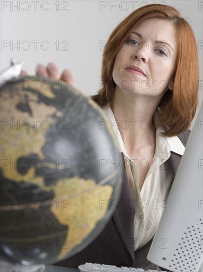 Woman at computer looking at globe.