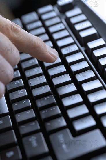 Closeup of finger and computer keyboard.