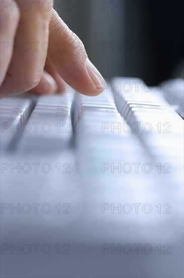 Closeup of finger and blurred keyboard.